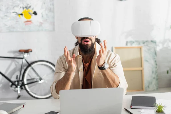 Freelancer Hispânico Espantado Headset Gesticulando Perto Laptop Borrado Casa — Fotografia de Stock