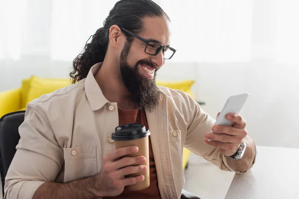 Homem Hispânico Alegre Óculos Segurando Café Para Usar Smartphone Casa Imagens De Bancos De Imagens Sem Royalties