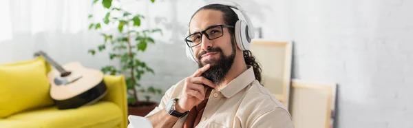 Sonhador Hispânico Homem Fones Ouvido Sorrindo Enquanto Ouve Música Perto Fotos De Bancos De Imagens