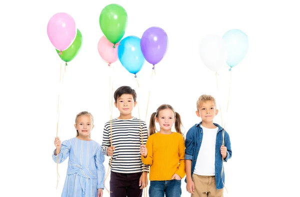 Smiling multiethnic children holding balloons isolated on white — Stock Photo