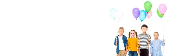 Enfants souriants et multiethniques tenant des ballons isolés sur une bannière blanche — Photo de stock