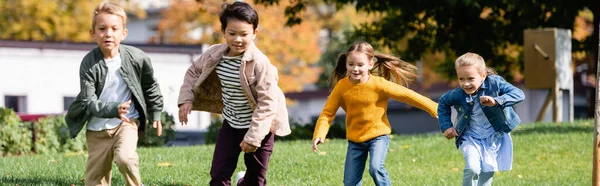 Fröhliche multikulturelle Kinder laufen im Park, Transparent — Stockfoto