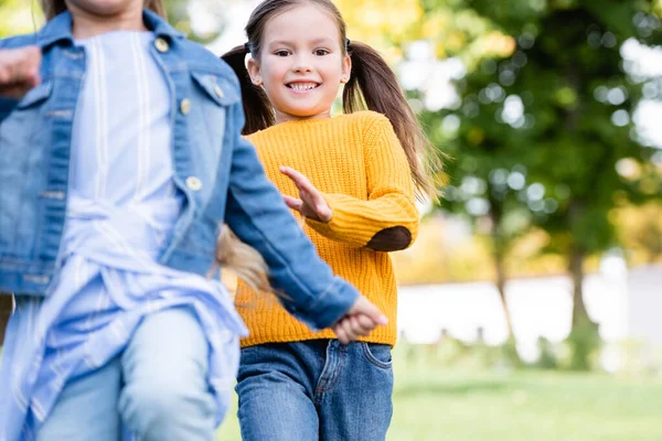 Fröhliches Mädchen läuft Freundin auf verschwommenem Weg im Park an — Stockfoto