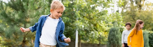 Lächelnder Junge steht neben Freunden auf verschwommenem Hintergrund im Park, Transparent — Stockfoto