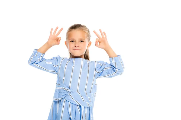 Lächelndes Kind zeigt OK-Geste, während es isoliert auf Weiß in die Kamera schaut — Stockfoto