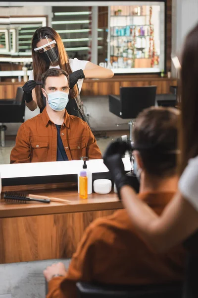Spiegelbild des Friseurs, der die Haare des Kunden schneidet, verschwommener Vordergrund — Stockfoto