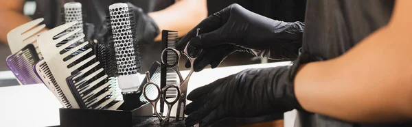 Visão parcial de barbeiro em luvas de látex colocando tesoura no suporte, banner — Fotografia de Stock
