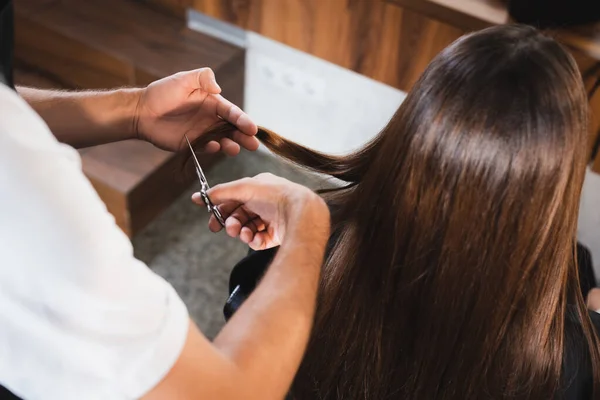 Barber cutting hair of woman on blurred foreground — Stock Photo