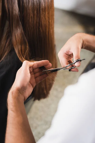 Visão cortada do cabelo de corte de cabeleireiro do cliente em primeiro plano borrado — Fotografia de Stock