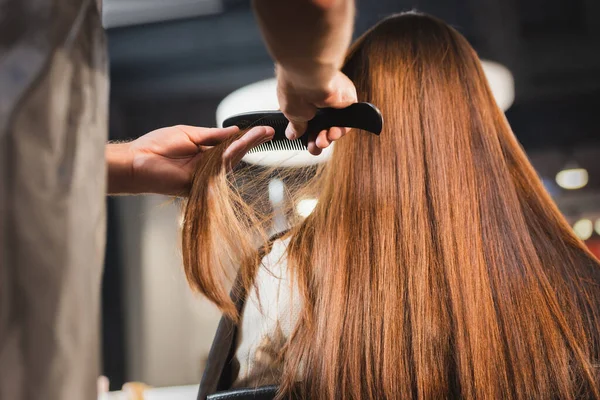 Cabeleireiro pentear o cabelo da mulher em primeiro plano borrado — Fotografia de Stock