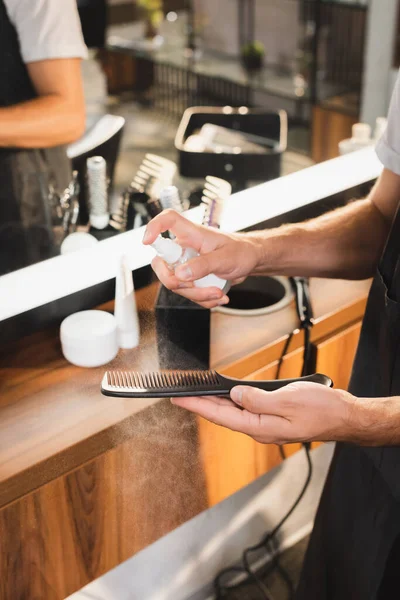 Обрезанный вид парикмахера, дезинфицирующего ножницы антисептическим спреем на рабочем месте — стоковое фото