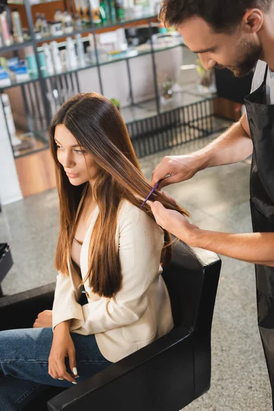 Jovem cabeleireiro pentear o cabelo da mulher na barbearia — Fotografia de Stock