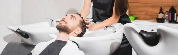 Cabeleireiro lavar o cabelo do jovem cliente na barbearia, banner — Fotografia de Stock