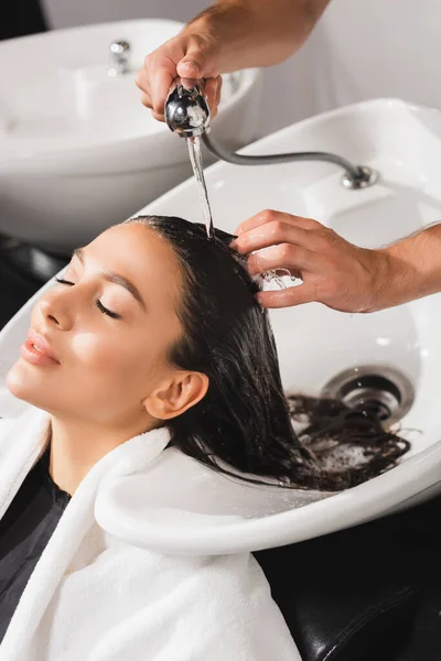 Cabelo de lavagem cabeleireiro de mulher com olhos fechados em barbearia — Fotografia de Stock