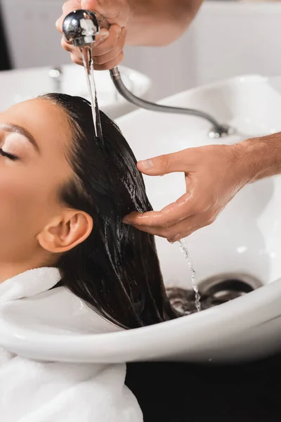 Vista ritagliata di parrucchiere che lava capelli di cliente in salone di bellezza — Foto stock