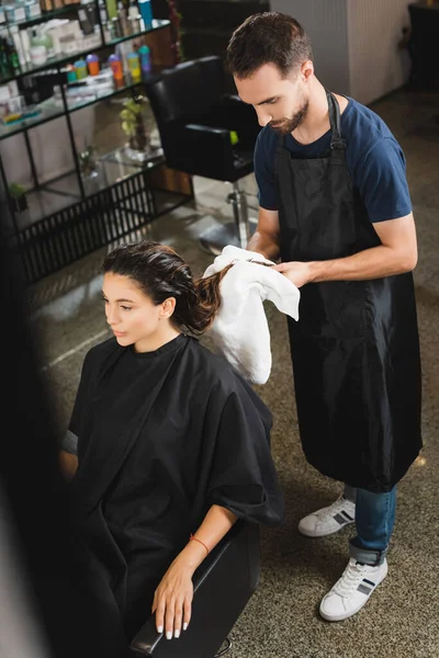 Vista ad alto angolo di barbiere pulire i capelli della donna con asciugamano, primo piano sfocato — Foto stock