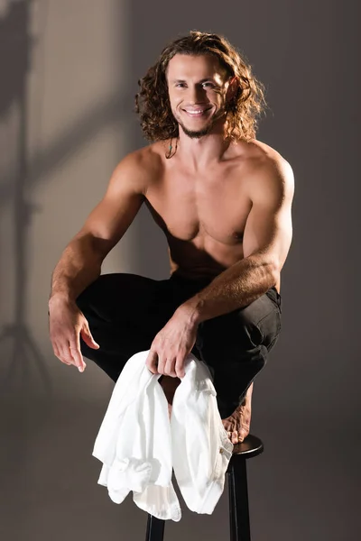 Счастливый сексуальный мужчина без рубашки с длинными волосами позирует на темном фоне — стоковое фото