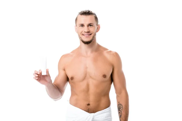 Sonriente sexy hombre sin camisa en toalla con crema de manos aislado en blanco - foto de stock