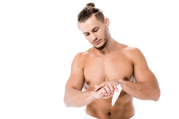 Сексуальный мужчина без рубашки в полотенце нанесение крема для рук изолированы на белом — стоковое фото