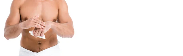 Vue recadrée de sexy homme torse nu en serviette appliquer crème pour les mains isolée sur blanc, bannière — Photo de stock