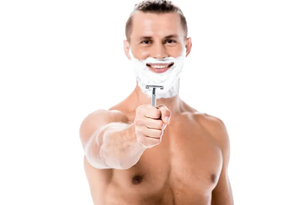 Smiling sexy shirtless man with foam on face holding razor isolated on white — Stock Photo