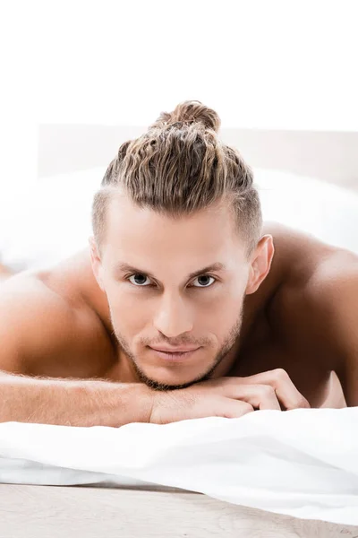 Сексуальный мужчина без рубашки позирует в постели изолированы на белом — стоковое фото