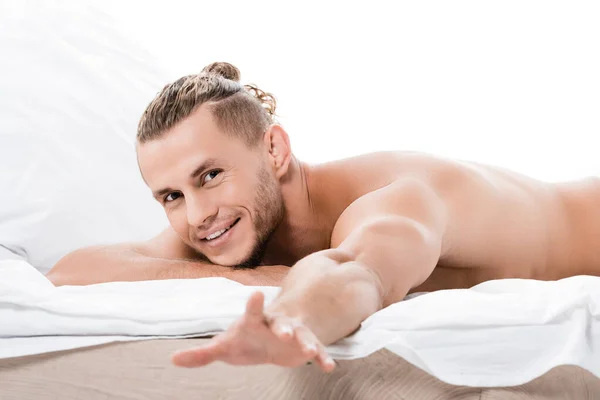 Sonriente sexy sin camisa hombre posando en cama aislado en blanco - foto de stock