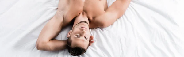 Top view of sexy shirtless man posing in bed, banner — Stock Photo