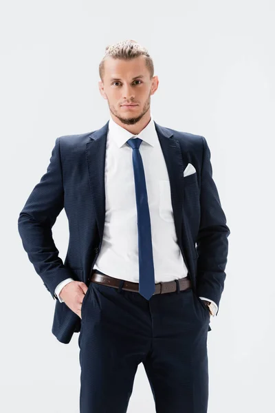 Joven hombre de negocios en traje posando con las manos en bolsillos aislados en blanco - foto de stock