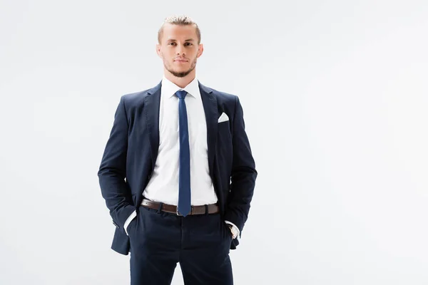 Молодий бізнесмен у костюмі з руками в кишенях ізольованих на білому — стокове фото