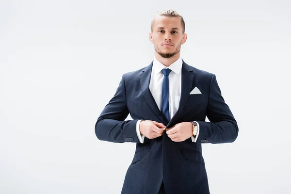 Joven hombre de negocios en traje abotonando chaqueta aislado en blanco - foto de stock