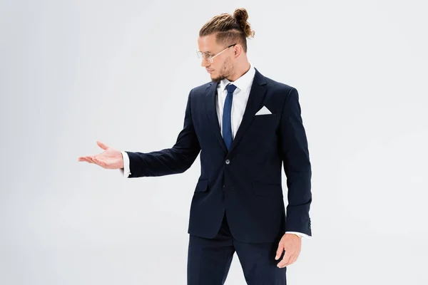 Jovem empresário de terno e óculos apontando com a mão isolada em branco — Fotografia de Stock
