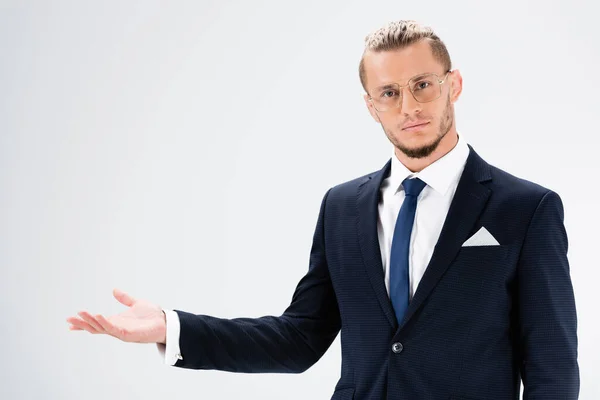 Joven hombre de negocios en traje y gafas apuntando con la mano aislada en blanco - foto de stock