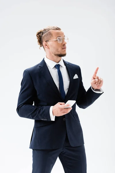 Jovem empresário de terno e óculos apontando para cima isolado em branco — Fotografia de Stock