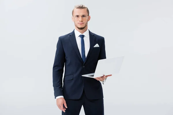 Jovem empresário de terno e óculos com laptop isolado em branco — Fotografia de Stock