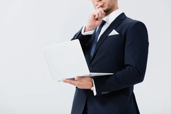 Visão recortada de jovem empresário pensativo em terno com laptop isolado em branco — Fotografia de Stock