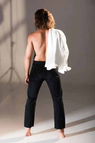 Back view of sexy shirtless man with long hair posing on dark background — Stock Photo