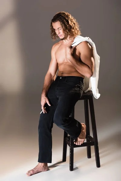 Сексуальный мужчина без рубашки с длинными волосами курение на темном фоне — стоковое фото
