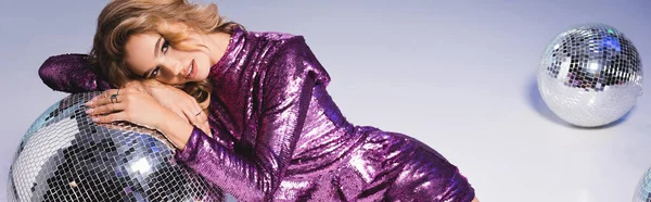 Елегантна жінка в сукні-шоу позує на підлозі з диско-кулями, банер — стокове фото