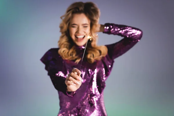 Mulher elegante feliz em vestido de lantejoulas com sparkler, fundo borrado — Fotografia de Stock