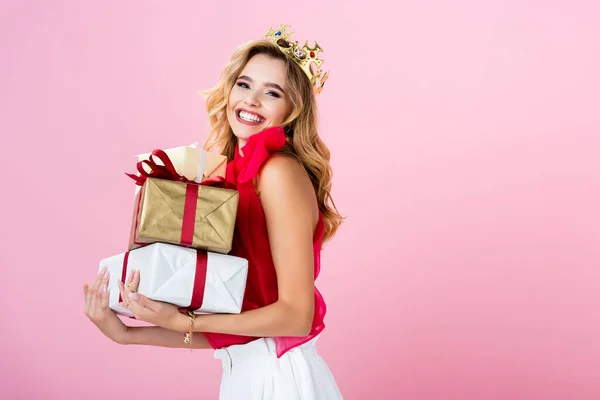 Mulher feliz elegante na coroa com presentes no fundo rosa — Fotografia de Stock