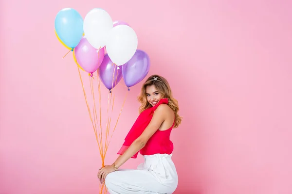 Elegante glückliche Frau in Krone mit Luftballons auf rosa Hintergrund — Stockfoto