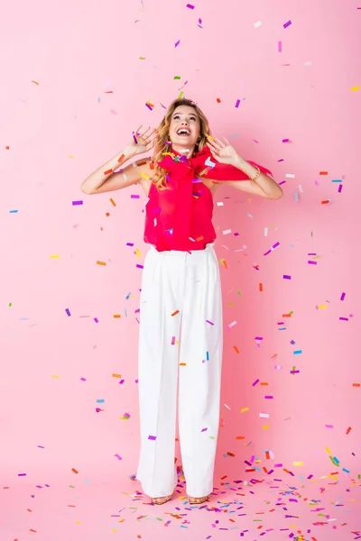 Elegant happy woman in crown under confetti on pink background — Stock Photo
