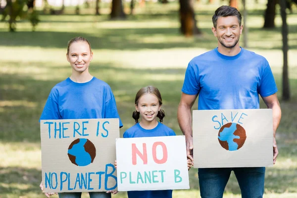 Familia sonriente de activistas sosteniendo pancartas con no hay inscripción planeta b, concepto de ecología - foto de stock