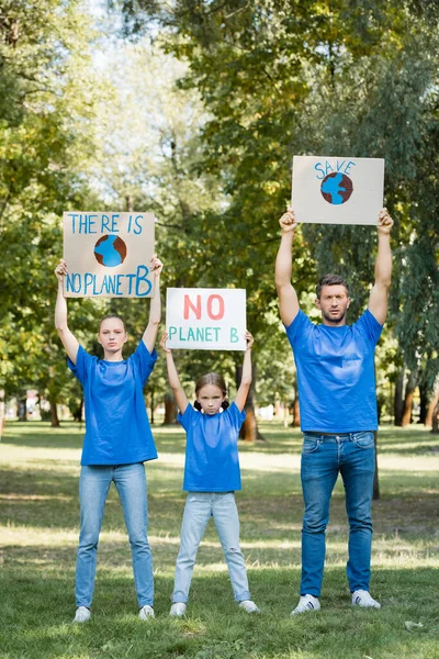 Family of activists holding placards with globe, save, and no planet b inscription in raised hands, ecology concept — Stock Photo