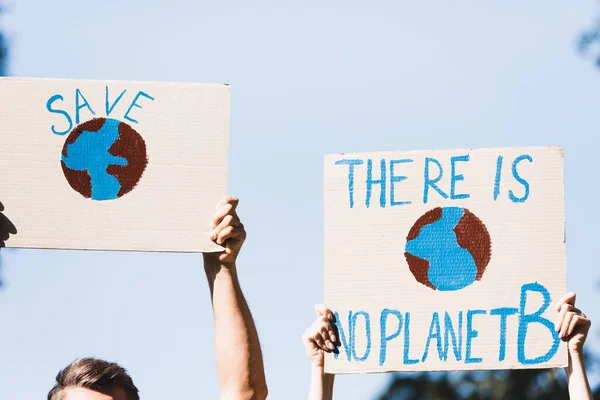 Visão cortada de voluntários segurando cartazes com globo e não há inscrição planeta b contra céu azul, conceito de ecologia — Fotografia de Stock