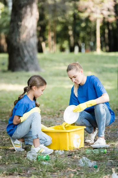 Mãe com filha coletando lixo plástico em recipiente com símbolo de reciclagem, conceito de ecologia — Stock Photo