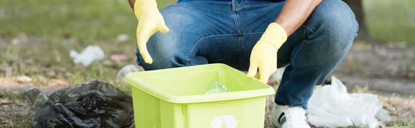 Vista recortada de voluntarios recogiendo basura de plástico en contenedor, pancarta - foto de stock