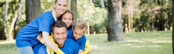 Familia de voluntarios abrazando y mirando a la cámara en el bosque, concepto de ecología, pancarta - foto de stock