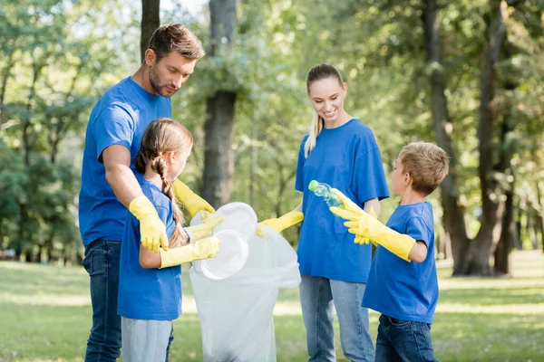 Семья волонтеров, собирающих пластиковые отходы в переработанные мешки, экологическая концепция — стоковое фото